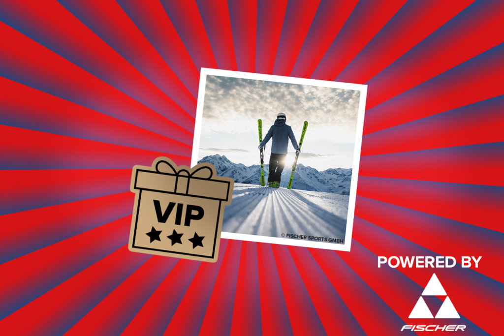 Banner mit rot-blauen Streifen, die sich von der Bildmitte nach außen ziehen. Mitten drin ein Foto, das einen einen einzelnen Skifahrer von hinten zeigt wie er bei Sonnenaufgang alleine auf der Piste steht, je einen Ski aufgestellt in der Hand und der Blick in die weiten Berge. Ebenfalls im Banner sind die graphische Darstellung eines VIP-Pakets und ein "Powered by" Schriftzug gefolgt von dem Fischer Logo.