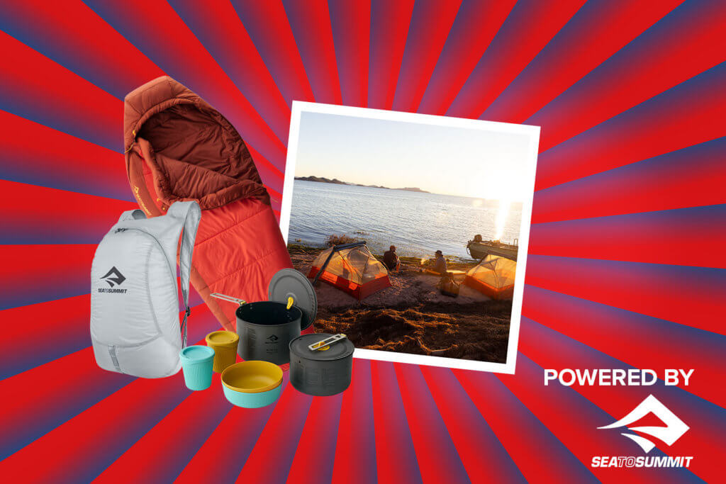 Banner mit rot-blauen Streifen, die sich von der Bildmitte nach außen ziehen. Mitten drin ein Foto, das zwei Herren beim Campen am Strand zeigt. Ebenfalls im Banner zu sehen sind Produktbilder (Rucksack, Töpfe, Schlafsack), und ein "Powered by" Schriftzug gefolgt von dem Sea to Summit.