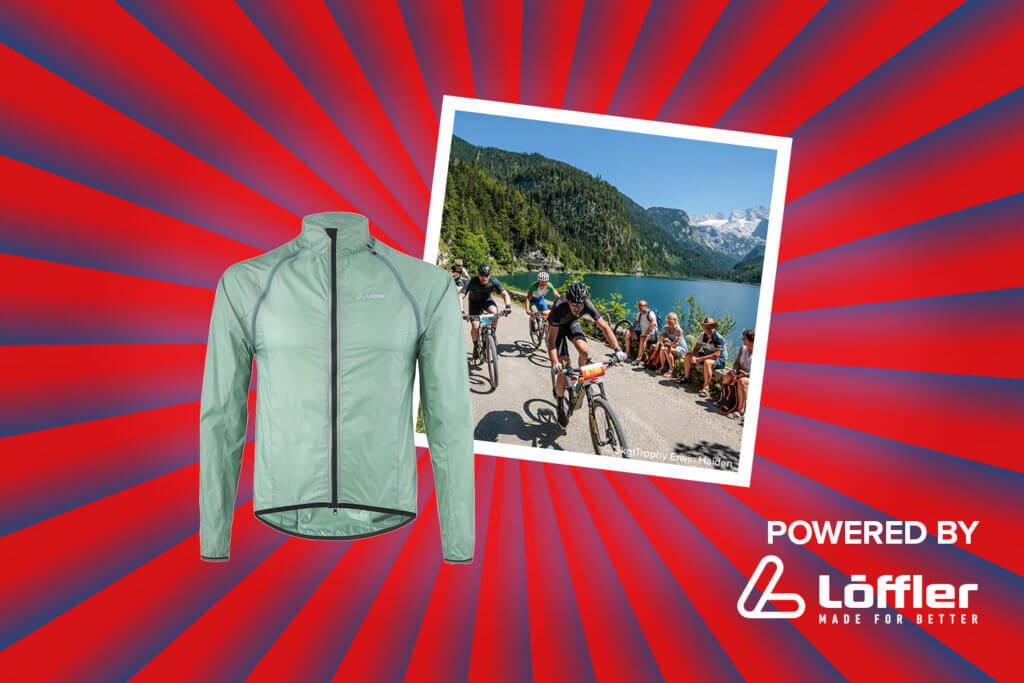 Banner mit rot-blauen Streifen, die sich von der Bildmitte nach außen ziehen. Mitten drin ein Foto, das mehrere Mountainbiker bei der Salzkammergut Trophy zeigt. Ebenfalls im Banner zu sehen sind eine hellgrübe Jacke von Löffler und ein "Powered by" Schriftzug gefolgt von dem Löffler Logo.